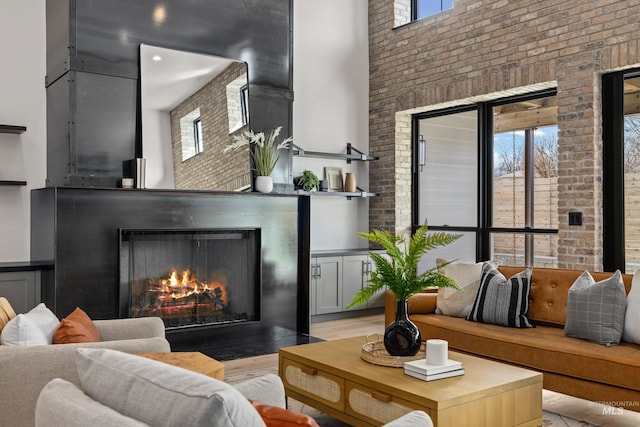 living room with brick wall, a high ceiling, and a lit fireplace