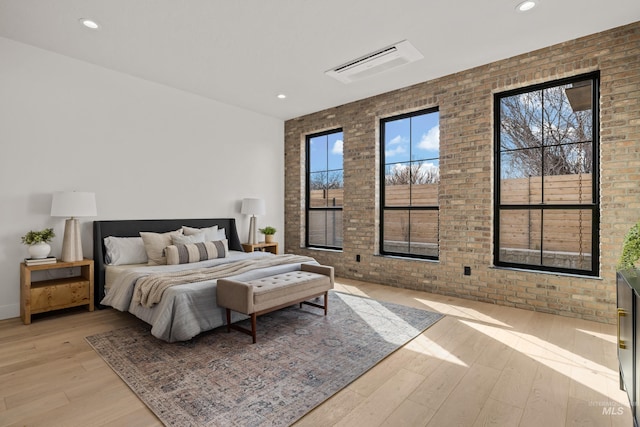 bedroom featuring recessed lighting, light wood-type flooring, and brick wall