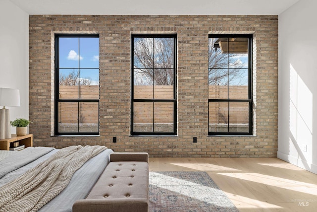 bedroom featuring wood finished floors and brick wall