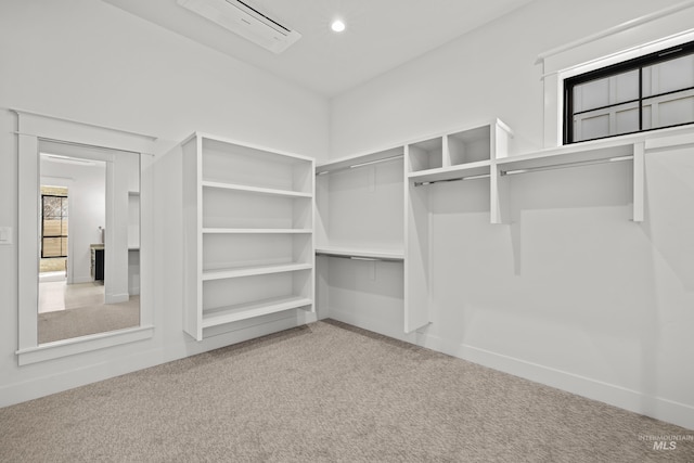 spacious closet with an AC wall unit and carpet flooring