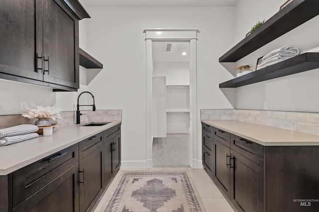 kitchen with visible vents, open shelves, dark brown cabinetry, light countertops, and a sink