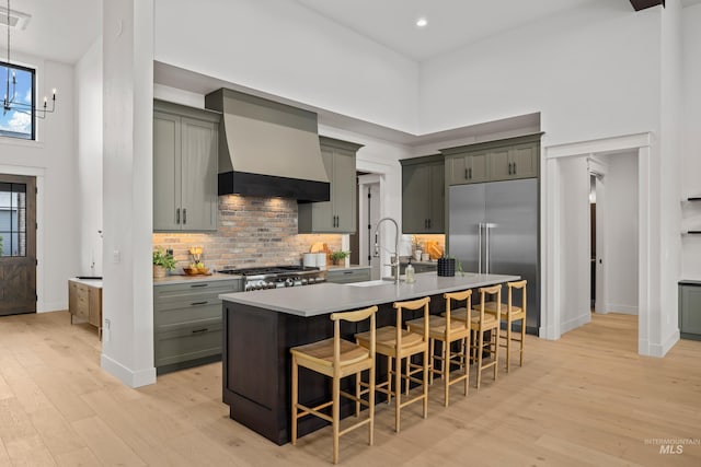 kitchen featuring a sink, a high ceiling, custom range hood, and built in fridge