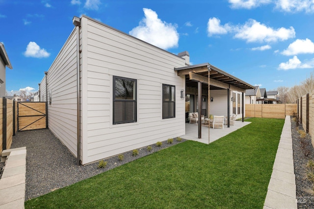 rear view of house with a patio, a lawn, a fenced backyard, and a gate