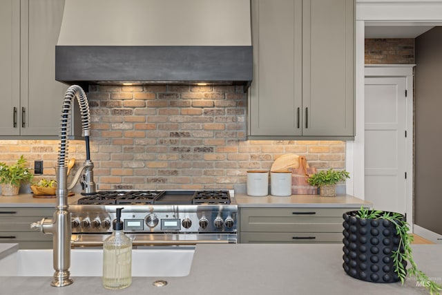 kitchen with decorative backsplash, gray cabinetry, light countertops, and wall chimney range hood