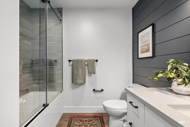 1620 W Bannock St # 303, Boise, ID 83702 - bathroom with baseboards, shower / bath combination with glass door, toilet, wood finished floors, and vanity