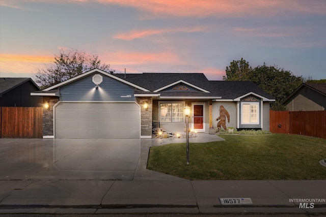 single story home featuring a lawn, fence, concrete driveway, an attached garage, and stone siding