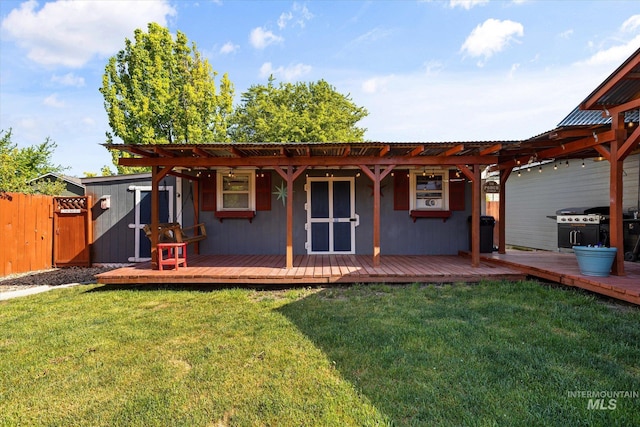 back of property with fence, a yard, and a deck