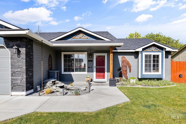 ranch-style house with roof with shingles, a front lawn, and stone siding