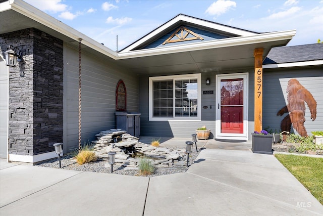 doorway to property with a porch and stone siding