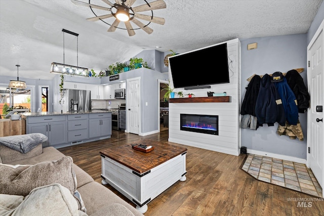 living area with a fireplace, a textured ceiling, a ceiling fan, baseboards, and vaulted ceiling