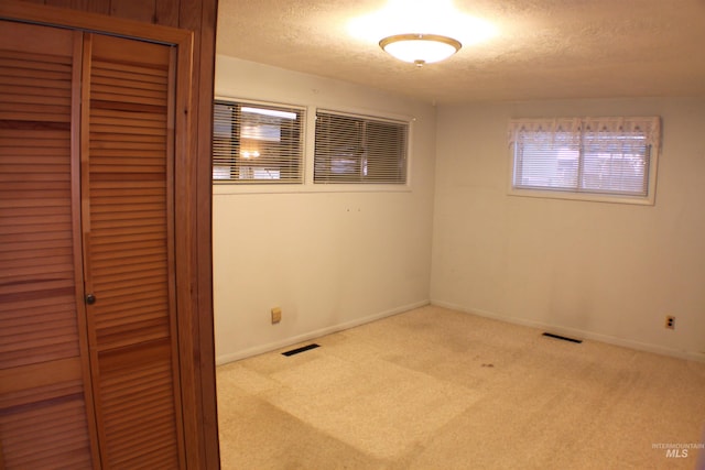 unfurnished room with light colored carpet and a textured ceiling