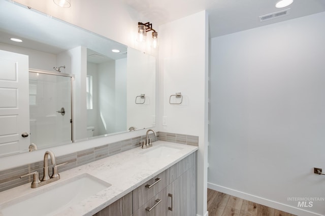 bathroom with a shower with door, backsplash, vanity, wood-type flooring, and toilet