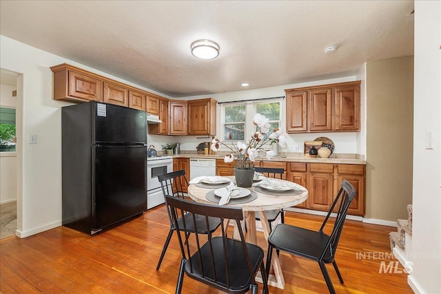 723 4th Ave N, Nampa, ID 83687 - kitchen with white appliances, under cabinet range hood, light countertops, brown cabinets, and light wood-style flooring
