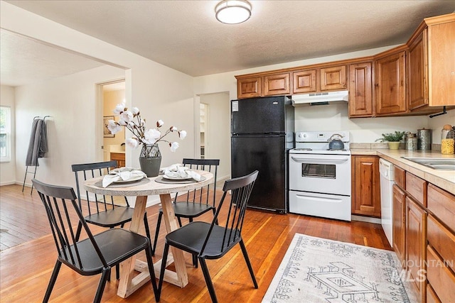 723 4th Ave N, Nampa, ID 83687 - kitchen featuring white appliances, under cabinet range hood, light countertops, wood-type flooring, and brown cabinetry