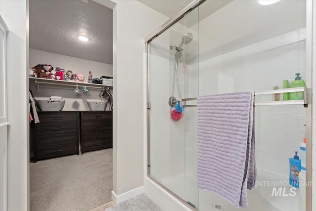 bathroom with a shower with door and a textured ceiling