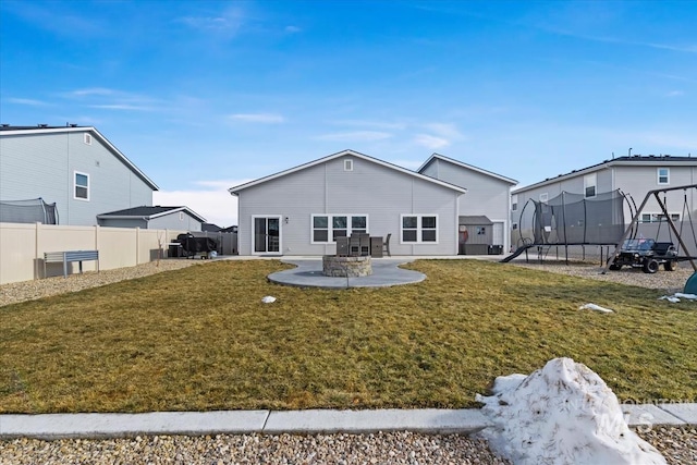 back of house with a trampoline, a lawn, and a patio area