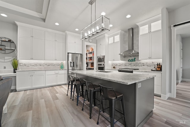 540 E Andes Dr, Kuna, ID 83634 - kitchen featuring wall chimney range hood, stainless steel appliances, tasteful backsplash, recessed lighting, and light wood-style floors