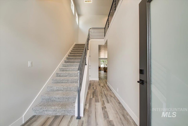 stairway with wood-type flooring and a high ceiling