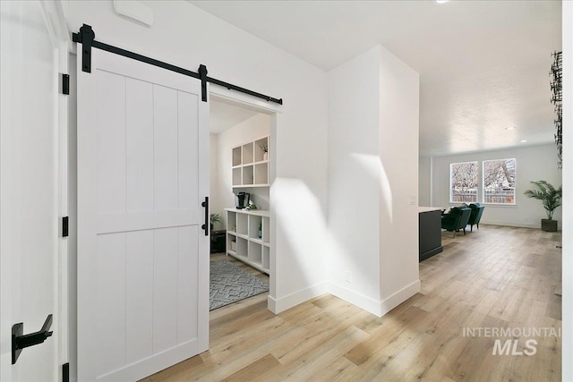 hallway featuring a barn door and light hardwood / wood-style flooring