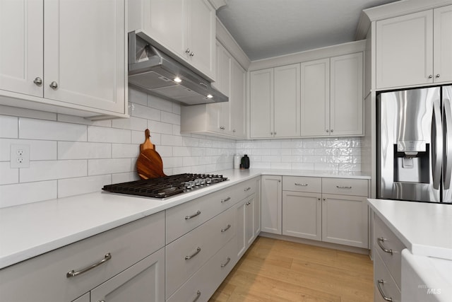 8333 S Updale Ave, Meridian, ID 83642 - kitchen with under cabinet range hood, tasteful backsplash, stainless steel appliances, and light countertops