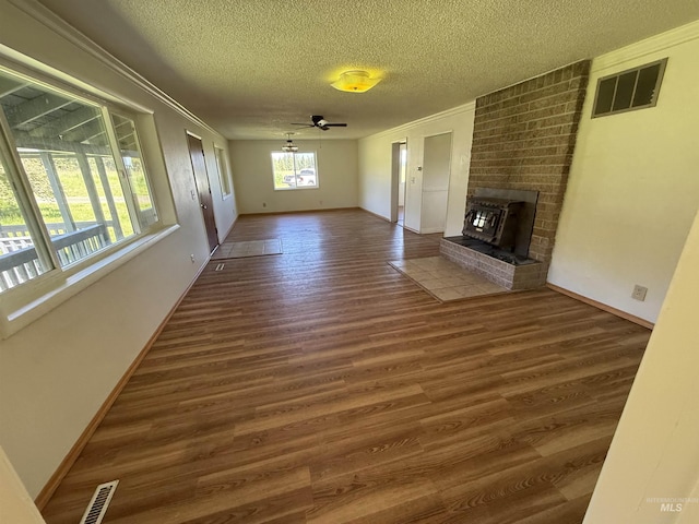 5656 Three Mile Rd, Weippe, ID 83553 - unfurnished living room featuring a textured ceiling, wood finished floors, a fireplace, ornamental molding, and baseboards