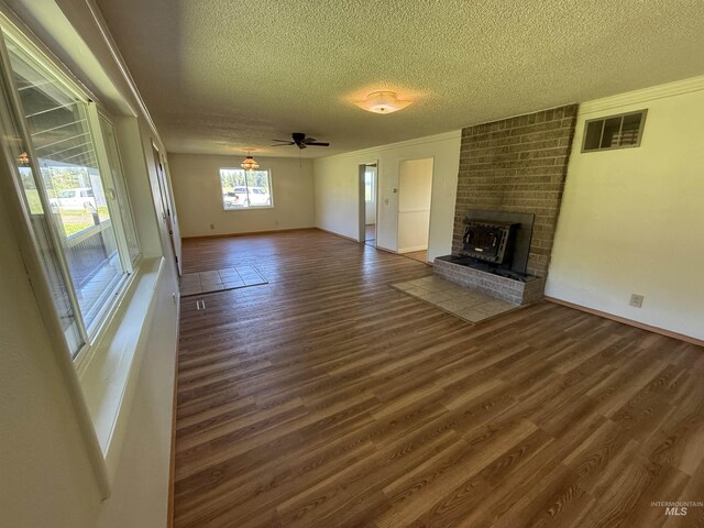 5656 Three Mile Rd, Weippe, ID 83553 - unfurnished living room with a textured ceiling, wood finished floors, a brick fireplace, crown molding, and baseboards