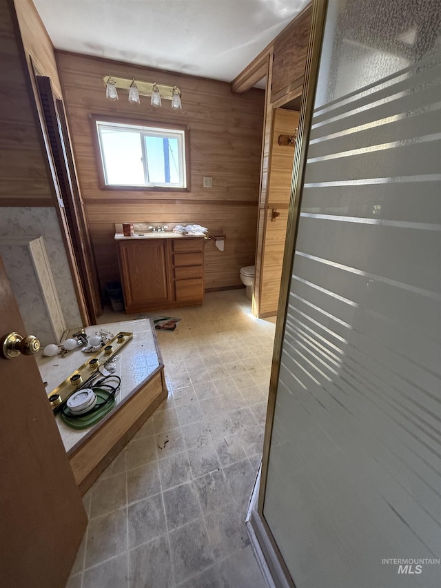 5656 Three Mile Rd, Weippe, ID 83553 - bathroom with vanity, toilet, wood walls, a stall shower, and stone finish flooring