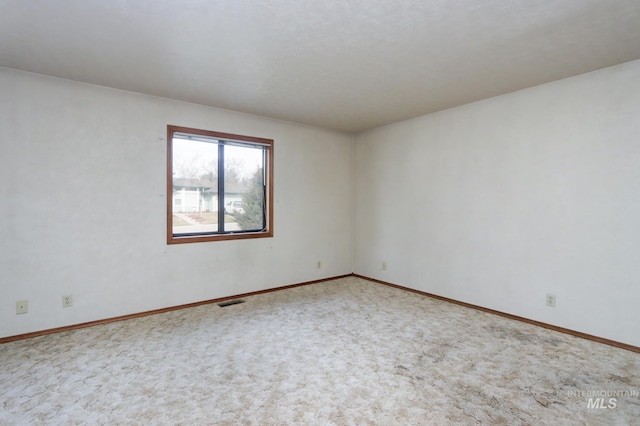 empty room with carpet flooring, baseboards, and visible vents