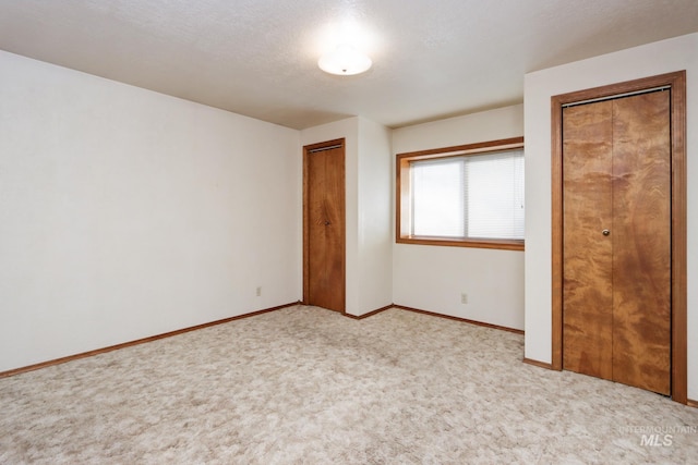 unfurnished bedroom featuring baseboards, multiple closets, and carpet floors