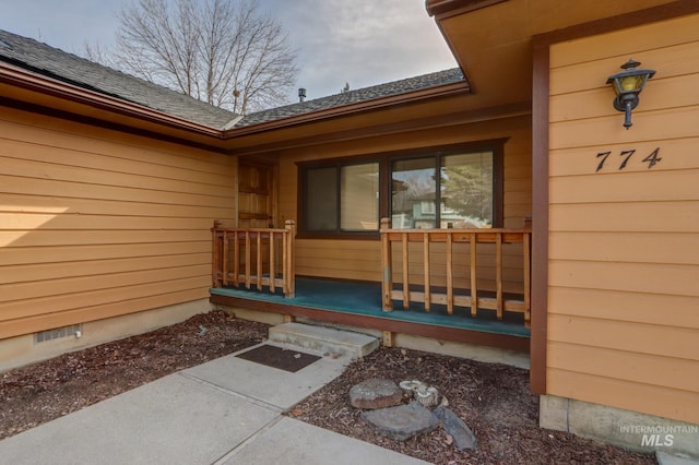 property entrance with crawl space, a porch, and a shingled roof