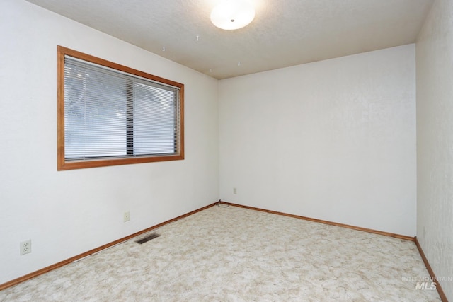 carpeted empty room with visible vents, a textured ceiling, and baseboards