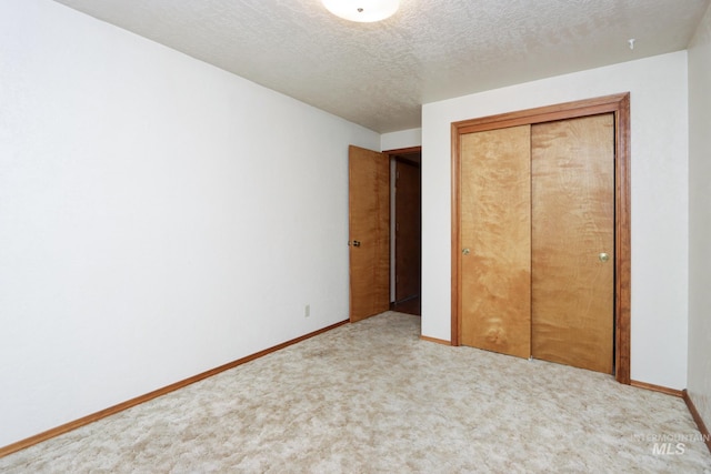 unfurnished bedroom featuring a textured ceiling, carpet, a closet, and baseboards