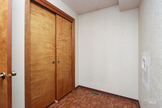 unfurnished bedroom with brick floor, baseboards, visible vents, and a closet