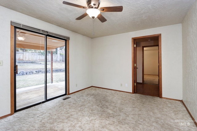 carpeted empty room with visible vents, baseboards, a textured ceiling, and a ceiling fan