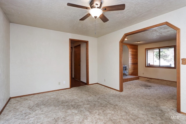 carpeted spare room with ceiling fan, baseboards, and a textured ceiling