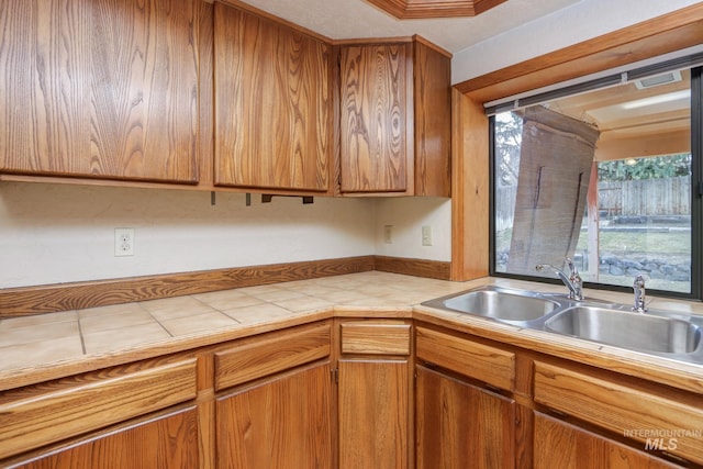 kitchen featuring tile counters, brown cabinets, and a sink