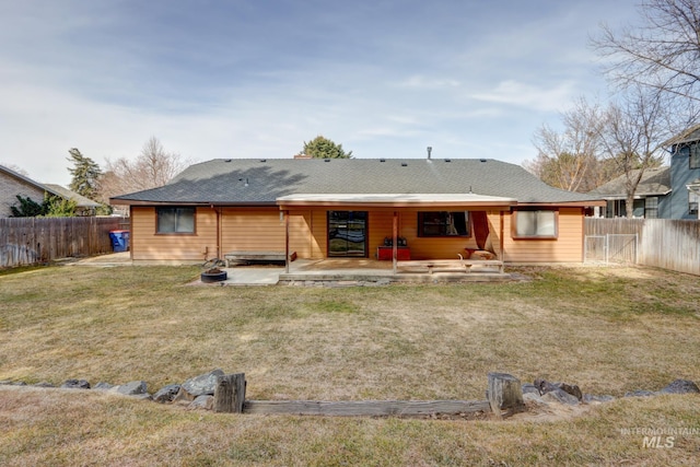 back of house featuring a patio area, a lawn, a shingled roof, and a fenced backyard