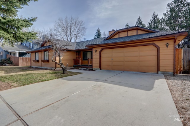 view of front of property featuring concrete driveway, an attached garage, fence, and a chimney