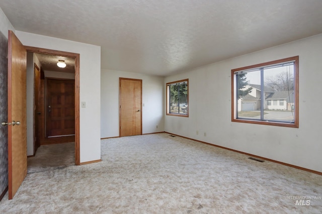 unfurnished bedroom with visible vents, a textured ceiling, baseboards, and carpet floors