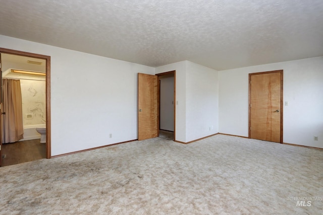 unfurnished room with carpet, baseboards, and a textured ceiling