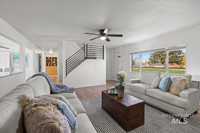 living room featuring a textured ceiling, light wood-type flooring, and ceiling fan