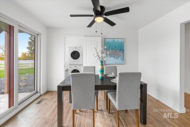 dining room featuring stacked washing maching and dryer, light wood-type flooring, and ceiling fan