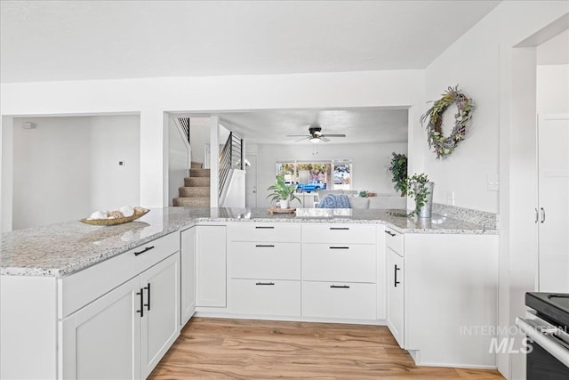 kitchen featuring light hardwood / wood-style floors, light stone counters, kitchen peninsula, ceiling fan, and white cabinets
