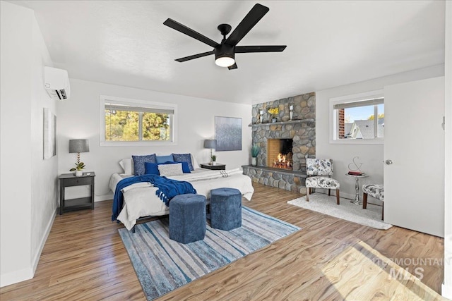 bedroom featuring ceiling fan, a wall mounted AC, multiple windows, and wood-type flooring