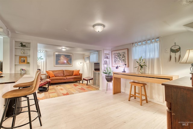 living area with built in features and light wood-type flooring