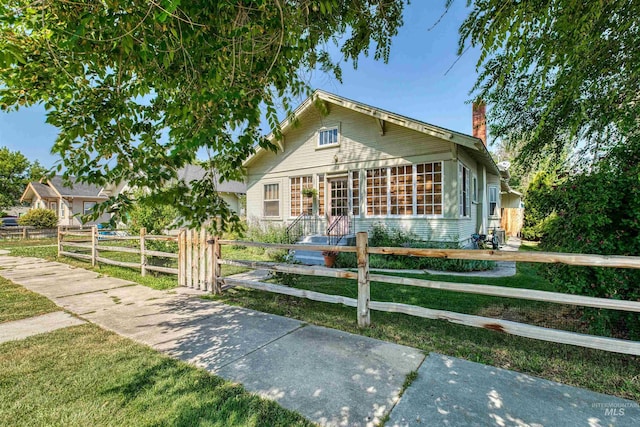 bungalow-style house with a fenced front yard and a chimney