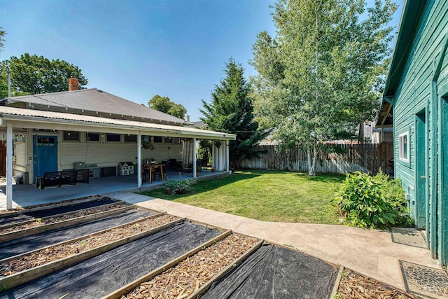 view of yard with a patio, a vegetable garden, and fence