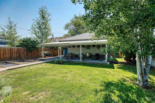 rear view of house with a fenced backyard, a yard, and a patio