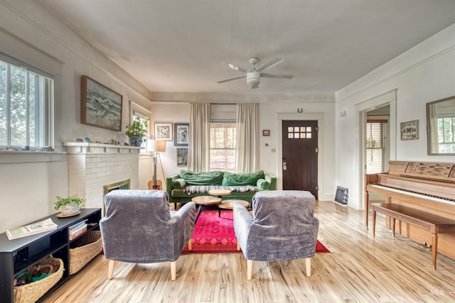 living area featuring a fireplace, a ceiling fan, and wood finished floors