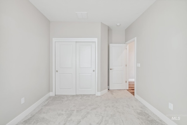 unfurnished bedroom featuring light colored carpet and a closet